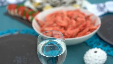 Sea style dining table outdoors with glass of wine, caprese salad, shrimp, Stock Footage 114693890