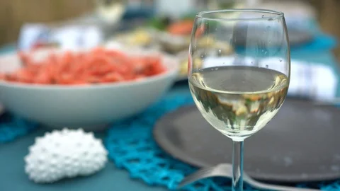 Sea style dining table outdoors with glass of wine, caprese salad, shrimp, Stock Footage 114693973
