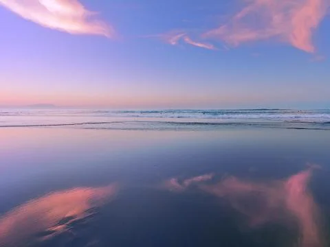 Sea at sunset with cloud reflections on sand Stock Photos
