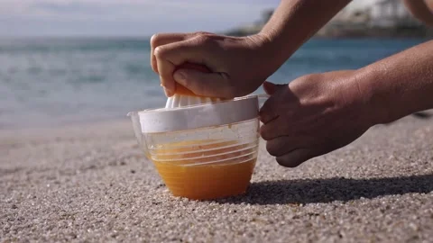 Sea surf in the background of squeezing orange juice Stock Footage 213989738
