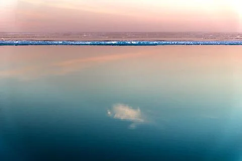 Sea surface with reflection of sky and clouds at sunset Stock Photos