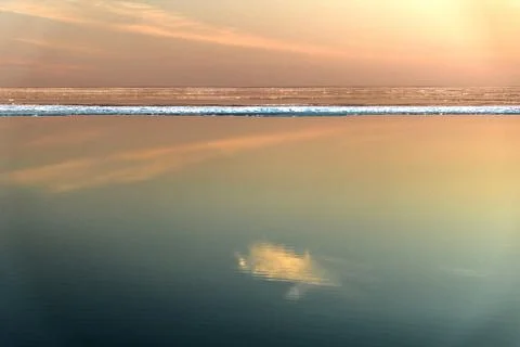 Sea surface with reflection of sky and clouds at sunset Stock Photos