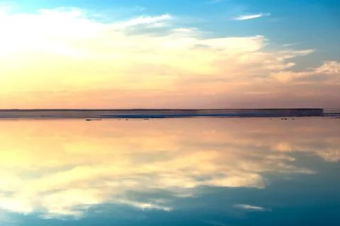 Sea surface with reflection of sky and clouds at sunset Stock Photos