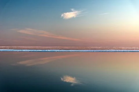 Sea surface with reflection of sky and clouds at sunset Stock Photos
