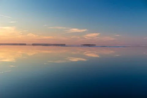 Sea surface with reflection of sky and clouds at sunset Stock Photos