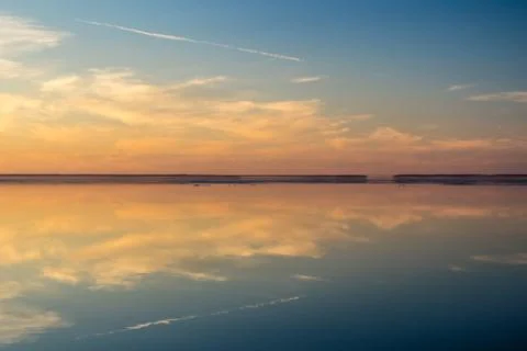 Sea surface with reflection of sky and clouds at sunset Stock Photos