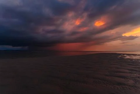 Sea at tide under dramatic sunset sky Stock Photos