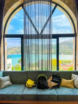 Sea view from a large semicircular window, a sofa with tourist backpacks and Stock Photos