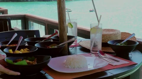 In a sea view restaurant, a waitress serves a table with rice plates Stock Footage 243671730