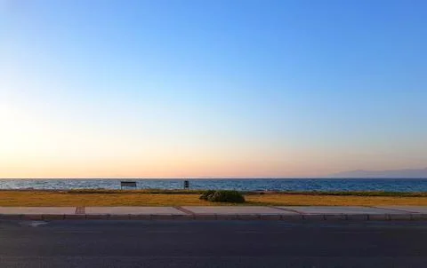 Sea view from road before sunset with an empty bench and a lonely bush Stock Photos