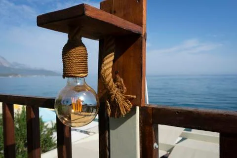 Sea view through a light bulb attached to a wooden holder Stock Photos
