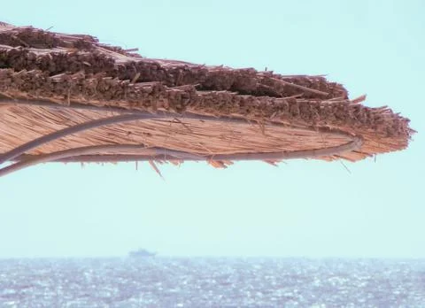 Sea view from under a straw beach umbrella. Ship on the background. Egypt. Stock Photos