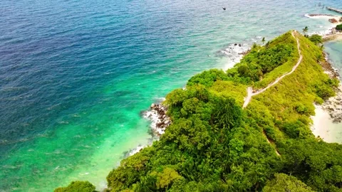 A sea water current keep sploshing the rocky island on the right side Stock Footage 243770359