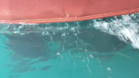 Sea water splashing on the lower back hull of a moving tugboat. Stock Footage 346579312