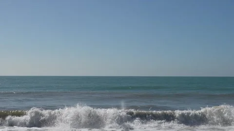 A sea wave breaks on a sandy beach. Abstract blue sky background. Nature and Video stock 326531924