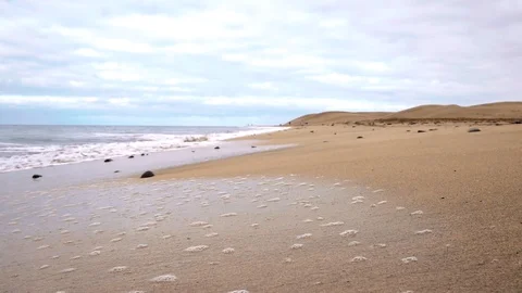 Sea wave with foam rolls on the sandy beach. The camera stands in the water Stock Footage 101755190