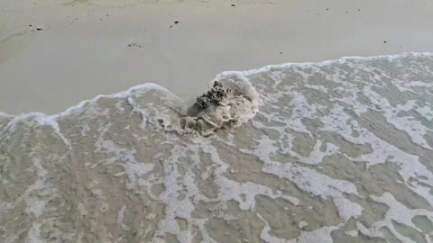 Sea Wave Forming Heart Shape Around Small Sand Mound on Beach Stock Footage 340175217