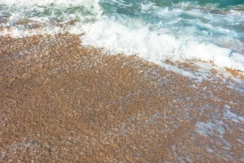 Sea wave rolling foam on to the sandy beach Photos