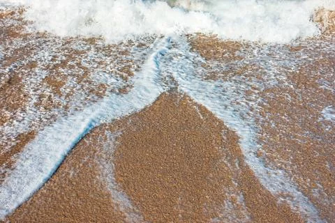 Sea wave rolling foam on to the sandy beach Stock Photos