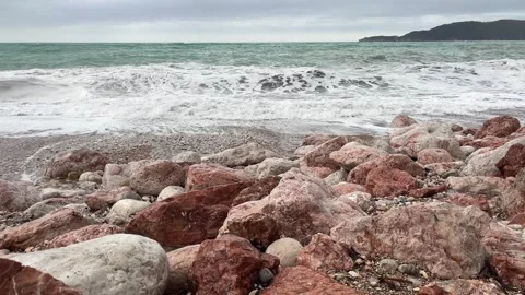 A sea wave rolls onto the coastal red stones, a static seascape. Stock Footage 263143731