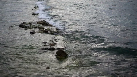 Sea wave rolls over a stone reef in slow motion Stock Footage 135757400