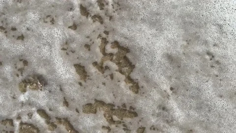 Sea wave washes away two footprints steps on the sand, vertical footage. Stock-Footage 224311089