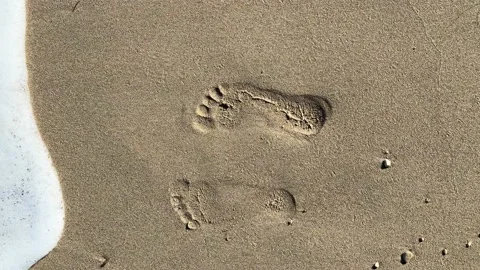 Sea wave washes away two footprints steps on the sand, vertical footage. Stock-Footage 225132078