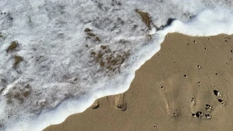Sea wave washes away two footprints steps on the sand, vertical footage. Stock-Footage 229569949