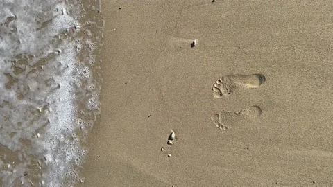 Sea wave washes away two footprints steps on the sand, vertical footage. 動画素材 234068960