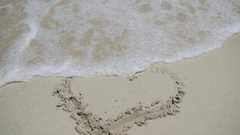 A sea wave is washing away the pattern on the sand with a sunny day 库存影片 74737484