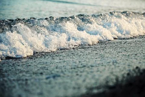 Sea wave wave in the rays of the daytime sun comes on the shore with pebbles Stock Photos