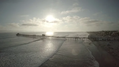 Sea waves approaching the coast alongside lengthy wooden jetty on a sunny day Stock Footage 79786842