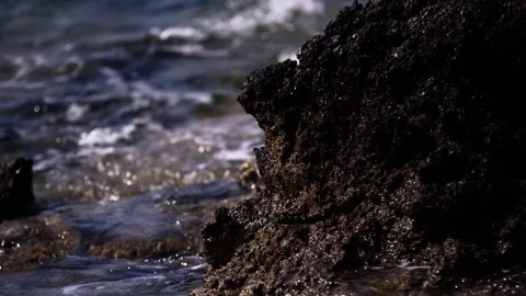 Sea waves break against dark porous coastal rock, close up nature footage Stock-Footage 341580962