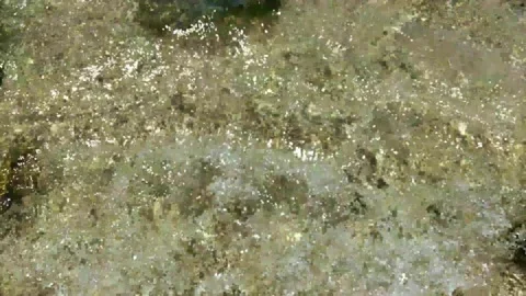 Sea waves break on stone, top view. Sun glare on the water surface and stones Stock Footage 135612255