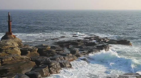 Sea waves breaking on the rocks with an old lighthouse Stock Footage 57640474
