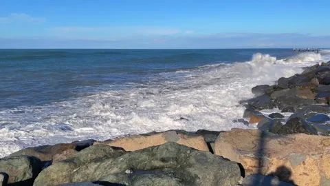 Sea waves breaking wide shot against a rocky shoreline Stock Footage 345361575