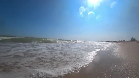 Sea waves cover a camera on a beautiful sandy beach on a sunny summer day. Video stock 87543643