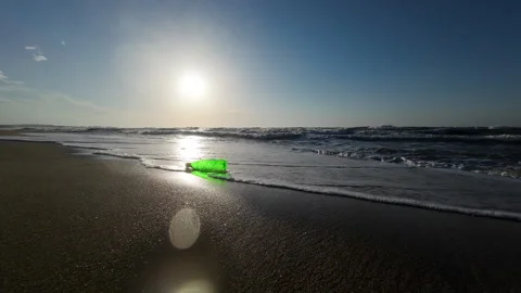 Sea waves crash into the camera. Green plastic container thrown into the sea Stock Footage 276711105