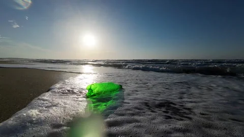 Sea waves crash into the camera. Green plastic container thrown into the sea Stock Footage 276711518