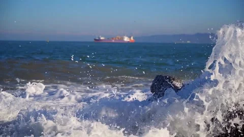 Sea waves crash on rocks with a ship background 스톡 동영상 333829533