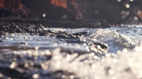 Sea waves crash softly against rocky shore in warm sunlight. Stock Footage 337410035