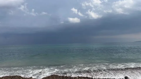 Sea waves crashing on pebble beach under dark stormy sky horizontal video frame Vídeos de archivo 343945293