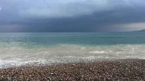 Sea waves crashing on pebble beach under dark stormy sky Stock Footage 343945308
