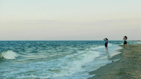 Sea waves on a deserted sandy beach, girls tourists  Stock Footage 54221315