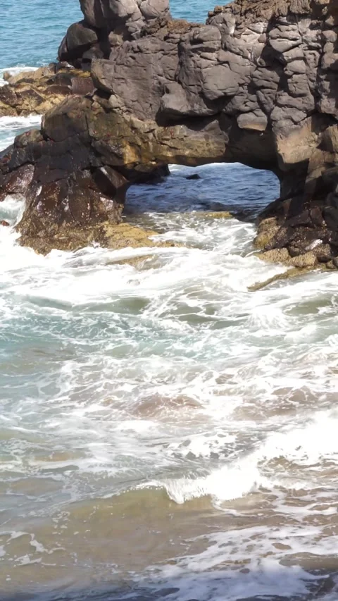 Sea waves entering rock formations of volcanic origin on the coast. Vertica.. Stock Footage 265565094