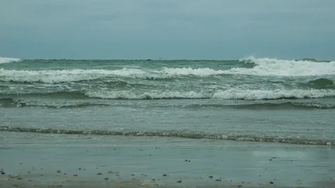 Sea waves flow on and off a beach on a cloudy day, the gray sky in the 스톡 동영상 73962562