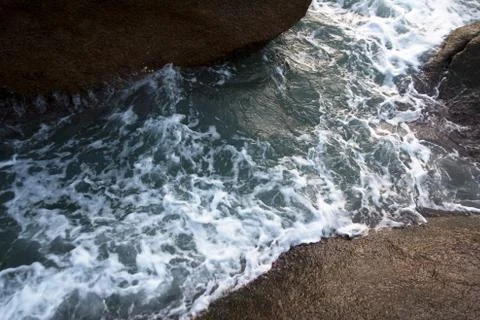 Sea waves foam between cliff stones Stock Photos