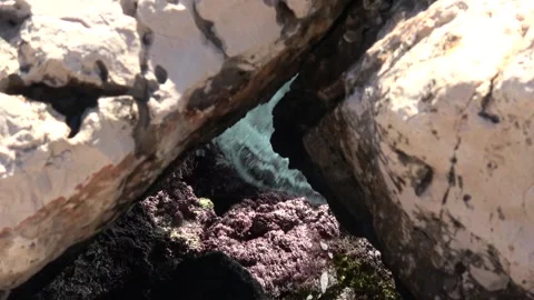 Sea waves foam crashing through narrow limestone rock crevice 動画素材 342394072