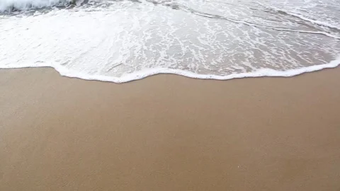 Sea waves with foam run to an empty sandy beach Video stock 153998499