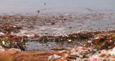 Sea waves full of litter hitting the beach. Huge dump in tropical paradise. M Video stock 127477217